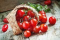 Small red cherry tomatoes spill out of a wicker basket on an old Royalty Free Stock Photo