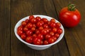 Small red cherry tomatoes in white bowl on wooden background Royalty Free Stock Photo