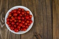 Small red cherry tomatoes in white bowl on wooden background Royalty Free Stock Photo