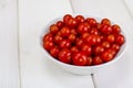 Small red cherry tomatoes in white bowl on wooden background Royalty Free Stock Photo