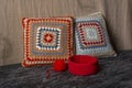 A small red decorative knitted basket and a ball of thread. Near the basket are two knitted pillows. Royalty Free Stock Photo