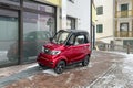 A small red electric car is parked near the house. Modern environmentally friendly urban transport. A smart car for two Royalty Free Stock Photo