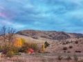 Small red farm shed in the dry brown hills under cloudy autumn sky in New Zealand