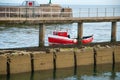 A small red fishing boat passes a pier on a calm day Royalty Free Stock Photo