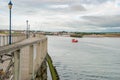 A small red fishing boat returning home passes a pier on a calm day Royalty Free Stock Photo