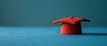 Small red graduation cap on blue surface Royalty Free Stock Photo