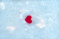 A small red heart lies on ice