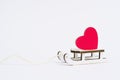 Small red heart on small wooden sleds on a white background.