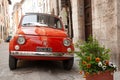 Small red iconic Italian car parked in traditional Italian village street Royalty Free Stock Photo