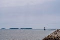 Small red lighthouse off coast of small seaport Royalty Free Stock Photo