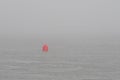 A small red navigation buoy in a foggy ocean Royalty Free Stock Photo