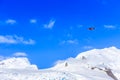 Small red plane flying among clouds over snow peaks and glaciers Royalty Free Stock Photo