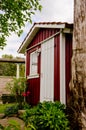 A small red shed with white window frames, a gardenhouse in a beautiful wild garden Royalty Free Stock Photo