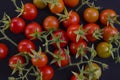 Small red tomatoes with calyxes on black floor Royalty Free Stock Photo