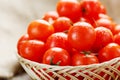 Small red tomatoes in a wicker basket on an old wooden table. Ripe and juicy cherry Royalty Free Stock Photo