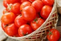 Small red tomatoes in a wicker basket on an old wooden table. Ripe and juicy cherry Royalty Free Stock Photo