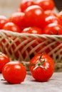 Small red tomatoes in a wicker basket on an old wooden table. Ripe and juicy cherry Royalty Free Stock Photo