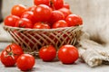 Small red tomatoes in a wicker basket on an old wooden table. Ripe and juicy cherry Royalty Free Stock Photo