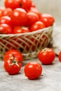 Small red tomatoes in a wicker basket on an old wooden table. Ripe and juicy cherry Royalty Free Stock Photo