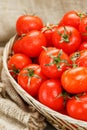 Small red tomatoes in a wicker basket on an old wooden table. Ripe and juicy cherry Royalty Free Stock Photo