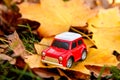 Small red toy car on a background of autumn leaves. Delivery concept. Copy space Royalty Free Stock Photo