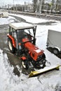 Small red tractor with snow plow for street cleaning