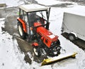 Small red tractor with snow plow for street cleaning in winter season Royalty Free Stock Photo