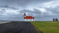 Small red and white church at Hellissandur village in Iceland with stormy sky