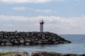 A small red and white lighthouse on a rocky pier Royalty Free Stock Photo