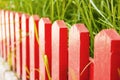 Small red wooden fence. Green grass grows behind the fence Royalty Free Stock Photo