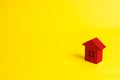 A small red wooden house stands on a yellow background. The concept of buying and selling real estate, renting. Search for a house Royalty Free Stock Photo