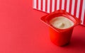 Small red yogurt cup with fruit yoghurt isolated on fun red background Royalty Free Stock Photo