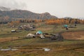 Small remote Siberian village in the late autumn under the mountain. Golden autumn landscape of rainy morning in the village of