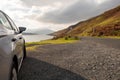 Small rented car parked off small road with beautiful scenery view. Killray fjord, county Mayo, Ireland. Cloudy sky, Mountains in