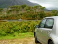 Small car parked, Pine island in the background, concept travel, visit Ireland.