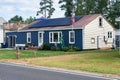 small residential home by the road with board siding on the facade and solar panels on the roof