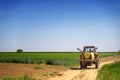 A small retro tractor rides along a path between green fields in countryside Royalty Free Stock Photo