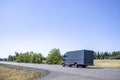 Small rig semi truck with huge box trailer making delivery running on the narrow winding road with summer meadows on the sides Royalty Free Stock Photo