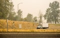 Small rig semi truck with refrigerated box trailer transporting cargo running on the road in smoke and smog from a forest fire