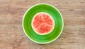 Small ripe halved watermelon on a green plate on a wooden tabletop