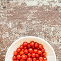 Small ripe organic cherry tomatoes in a bowl on old wood table Royalty Free Stock Photo