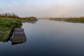 A small river covered with fog and a wooden bridge. Morning autumn fog over meadows and water Royalty Free Stock Photo