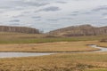 A small river flowing through meadows and agricultural fields. spring. Cloudy sky. Selective focus Royalty Free Stock Photo