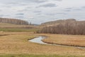 A small river flowing through meadows and agricultural fields. spring. Cloudy sky. Selective focus Royalty Free Stock Photo