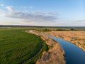 Small river meanders in the midst of green fields and meadows at sunset. Beautiful landscape with a bird`s eye view on a summer ev Royalty Free Stock Photo