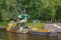 Small river non self-propelled multi-bucket dredger with a barge cleans the river Moika