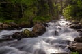 small river runs from the mountain through the stones and a colorful forest under the sunlight and along a path Royalty Free Stock Photo