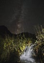 Small river stream waterfall in the mountains on a starry night against the background of the starry sky of the milky way at night