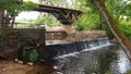 On small river there is an artificial waterfall under wooden bridge in the forest Royalty Free Stock Photo