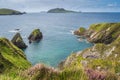 Small rocky islands at Dunquin Pier surrounded by turquoise water and tall cliffs, Dingle